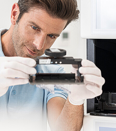 Lab employee at the 3D printer, holding the printed output